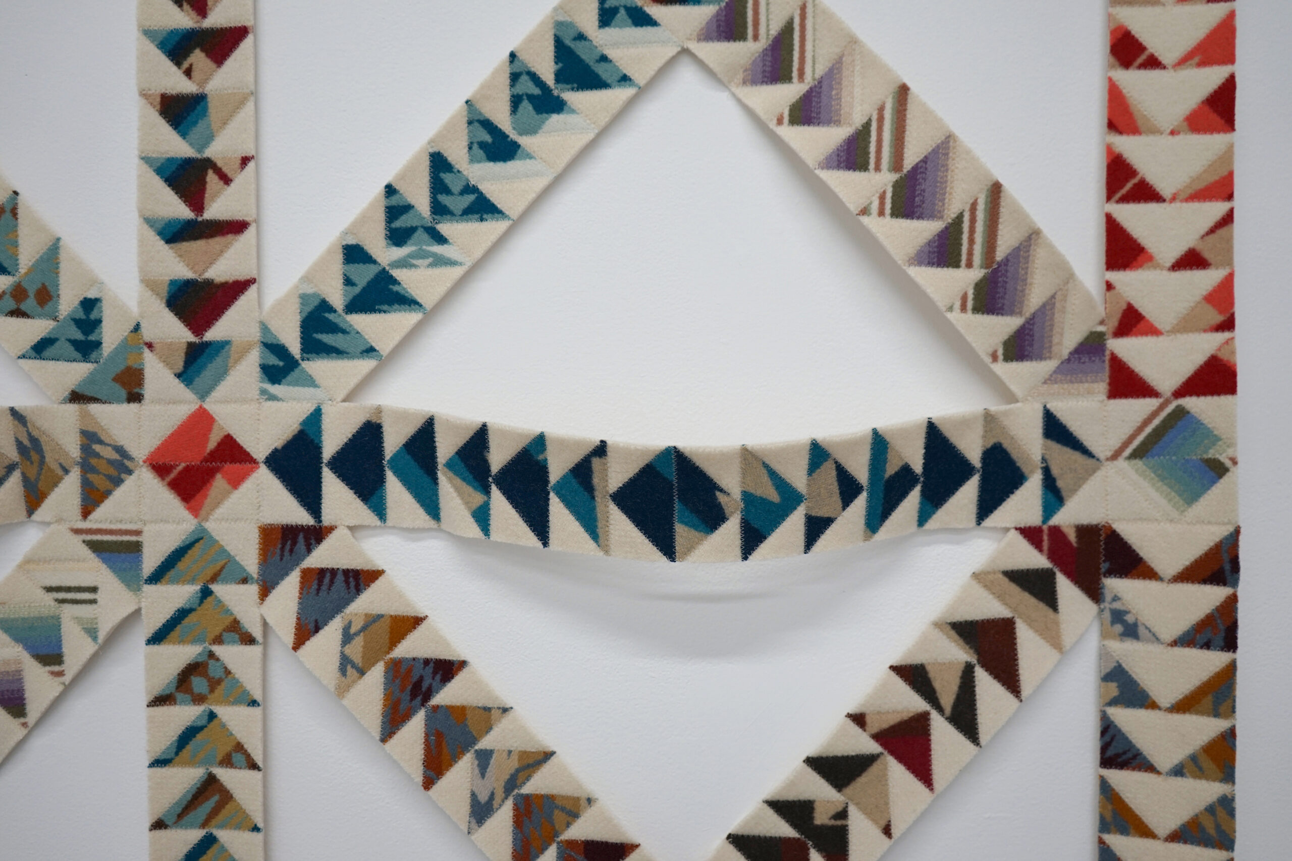 detail of multicolored pieced quilt lattice in white borders