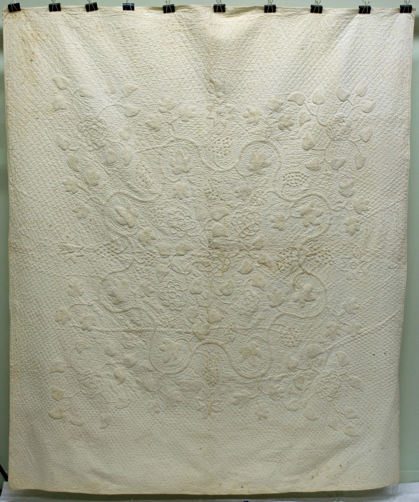 an elaborate floral design in a white-on-white quilted bedcover